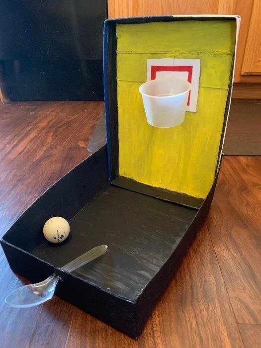 Mini cesto de basquetebol feito com caixa de papelão pintada e copo de plástico